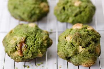 Closeup of fresh baked matcha cookies on white wooden background.