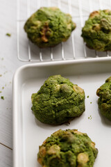 Closeup of fresh baked matcha cookies on white wooden background.