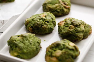 Closeup of fresh baked matcha cookies on white wooden background.