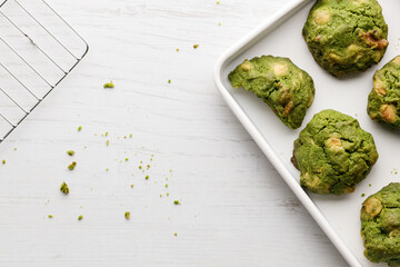 Closeup of fresh baked matcha cookies on white wooden background.