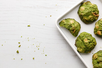 Closeup of fresh baked matcha cookies on white wooden background.