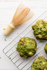 Closeup of fresh baked matcha cookies with Chasen, bamboo whisk, on white wooden background.
