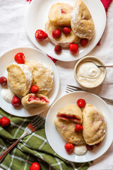 Traditional Ukrainian dumplings with strawberry filling, served with sour cream and fresh berries. Perfect for food blogs, packaging, or cultural cuisine projects.