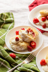 Traditional strawberry vareniki topped with sour cream and served with whole berries. Great for food prints, magazine features, or recipe visuals.