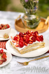 Creamy crepe cake topped with strawberries and honey. Summer afternoon dessert outside.
