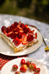 Delicate crepe cake topped with juicy strawberries. Perfect summer food for a picnic table.
