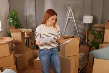 A person stands amidst packed boxes and paperwork, preparing for a move into a new home. Sunlight...