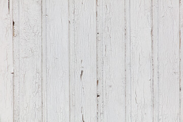 A white wooden wall with a lot of cracks and holes