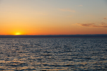 The ocean is calm and the sky is orange