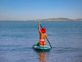 young women in red bikini  riding  on sup surfing in the sea at sumer time