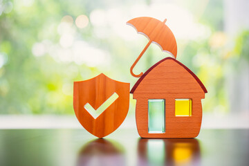 House model with umbrella and shield protect icon on wood table, concepts of contract to buy, get insurance or loan real estate or property background.	
