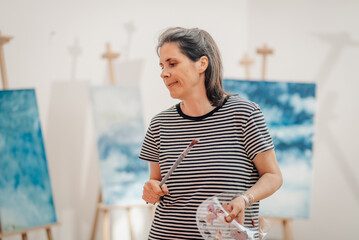 Female artist holding paintbrush and palette in art studio