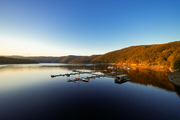 View of the Rursee at the dam near Heimbach-Schwammenauel. Landscape at the lake at sunset. Nature in the Eifel National Park.
