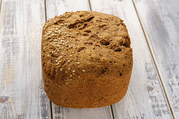 Whole grain bread loaf with sesame seeds and flax seeds on a rustic wooden table, healthy fresh baked snack food, homemade natural delicious bakery product concept.
