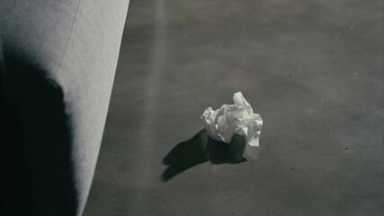 A crumpled tissue remains on the floor beside an empty couch.