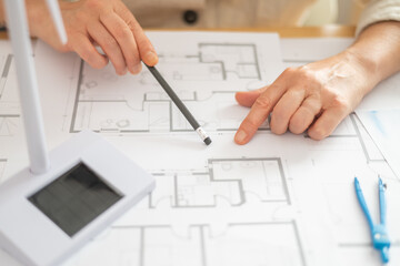 Engineers analyzing blueprints for a sustainable building project, incorporating renewable energy...