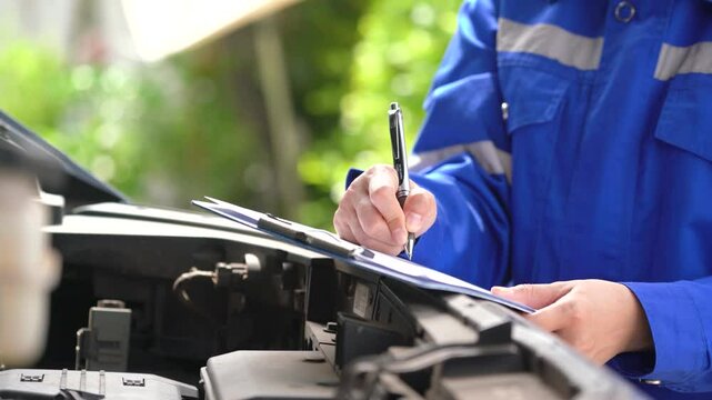 Action of a repairman is checking on multi-point checklist form during perform service the car parts. Industrial working scene, close-up and selective focus.