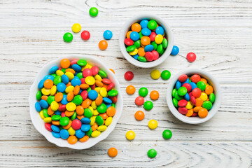 different colored round candy in bowl and jars. Top view of large variety sweets and candies with...