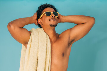 young latino man smiling with sunglasses and towel in swimsuit isolated on background, summer