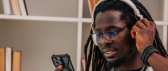 young afro man with headphones and mobile phone indoors