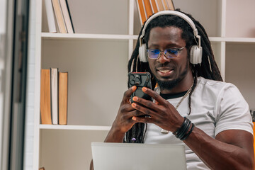 young afro man with headphones and mobile phone indoors