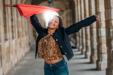 young latina woman with umbrella on the street excited with joy