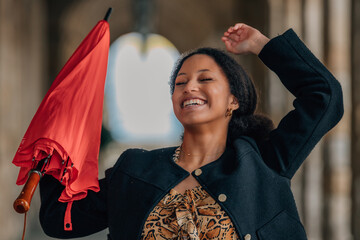 young latina woman with umbrella on the street excited with joy