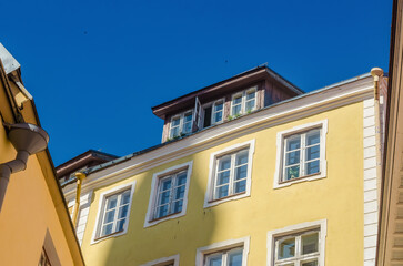Sunny yellow building facade with dormer windows and clear blue summer sky. High quality photo