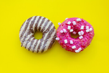 two donuts on yellow background, sweet donuts background, chocolate donut and pink donut with marshmallow