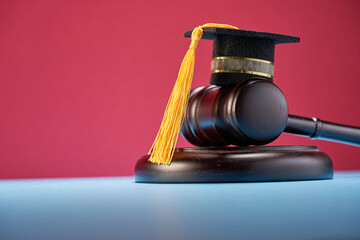small mortarboard and gavel  on table against red background