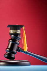 small mortarboard and gavel  on table against red background