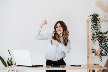 Strong businesswoman flexing muscles in office