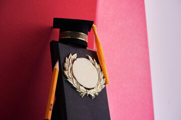 small mortarboard on award plaque against red background