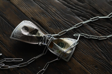 Chained Dollar Bill on Rustic Wooden Table Representing Financial Constraints and Money Security
