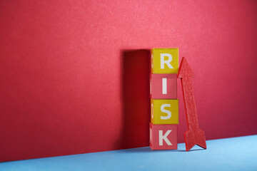toy block with text RISK and red arrow pointing up.