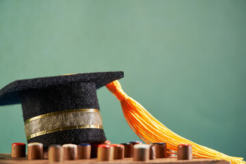 small mortarboard on portable chessboard against chalkboard