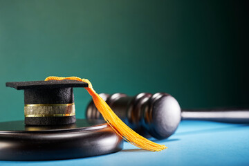 small mortarboard on mallet with gavel against blue and green background