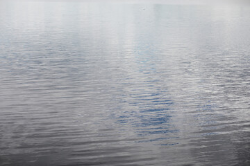 Tranquil Water Surface Reflecting Sky and Clouds at Dawn