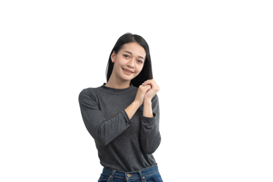 Young woman smiling in gray shirt with hands clasped together, expressing joy and optimism, showcasing positivity and warmth in casual setting