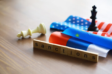 Sanctions Concept with USA and Russia Flags, Chess Pieces, and Scrabble Letters on Wooden Table