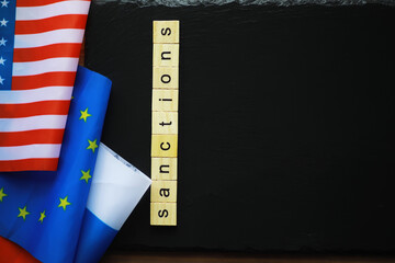 Sanctions Concept with USA and EU Flags and Wooden Blocks on Black Background