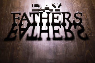 Father's Day celebration concept with wooden letters casting shadows on a wooden surface