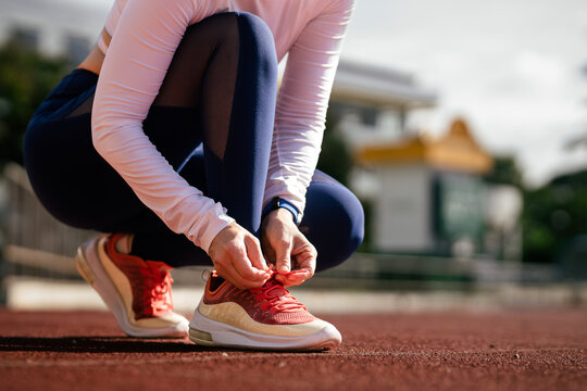 Close-up of female runners tying up their shoelaces before running in the stadium