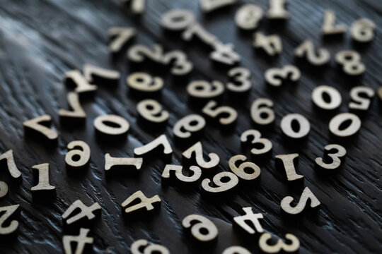 Close-Up of Scattered Wooden Numbers on Dark Wooden Surface - Mathematics and Education Concept