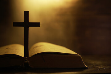 Silhouette of a Cross on an Open Bible with Warm Ambient Light in the Background