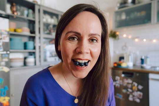 Woman eating blueberries in a kitchen at home