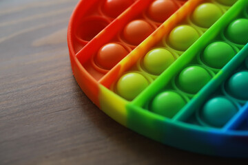 Vibrant Rainbow Pop It Toy on Wooden Surface for Stress Relief and Sensory Play
