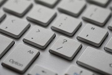Close-Up of White Keyboard Keys with Focus on Question Mark Key for Digital Workspace Concept.