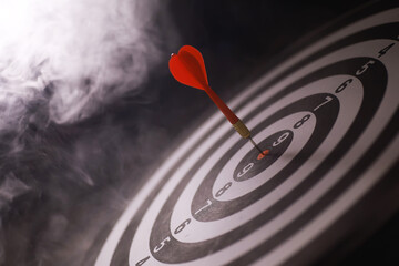 Red Dart Hitting Bullseye on Dartboard with Misty Background - Precision, Success, and Achievement...