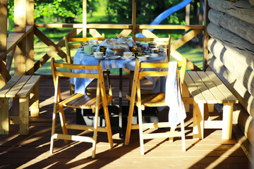 Cozy Outdoor Dining Set on Sunlit Wooden Porch with Breakfast Spread